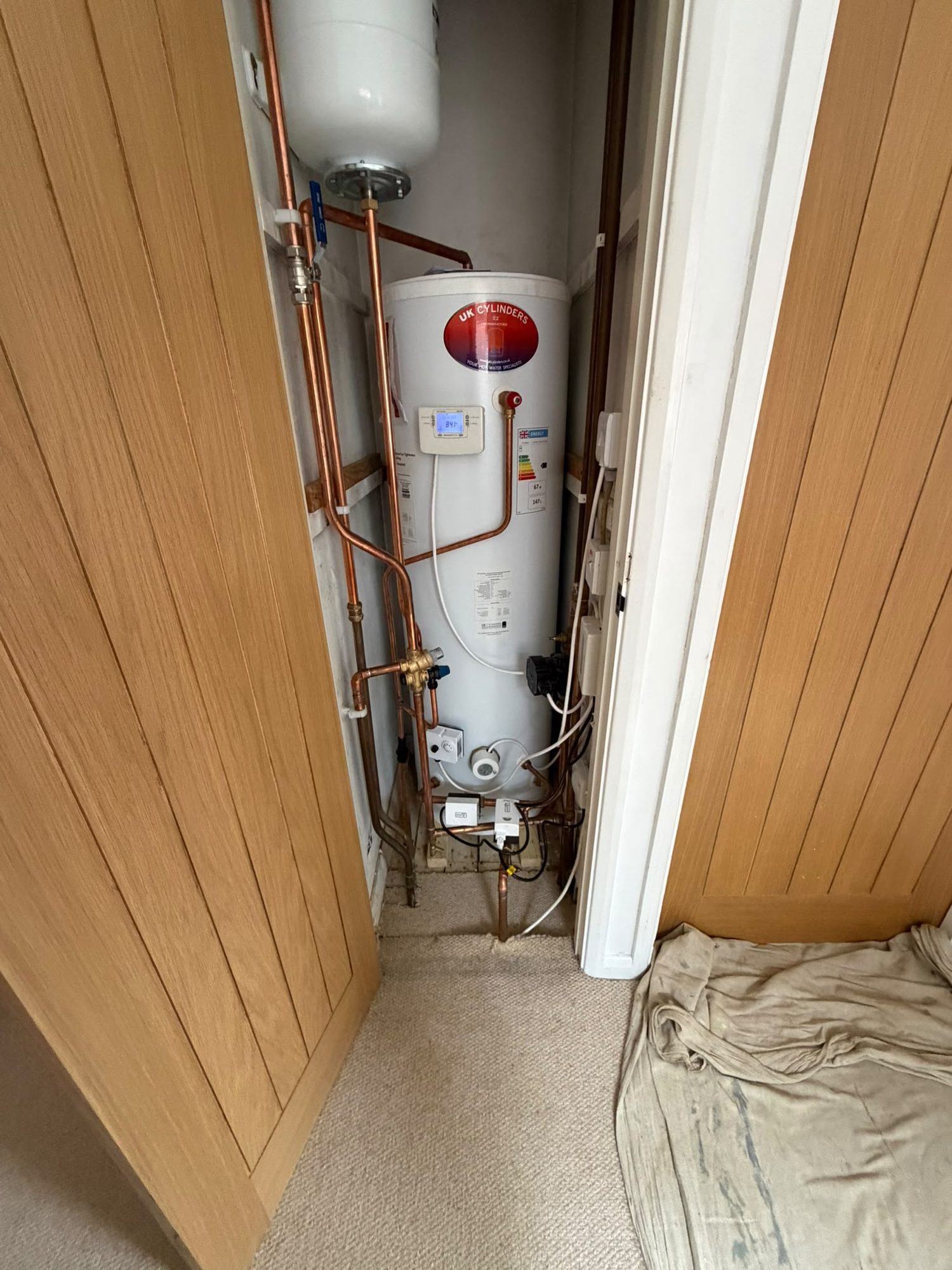 Unvented hot water cylinder and gas system pipework installed in an airing cupboard