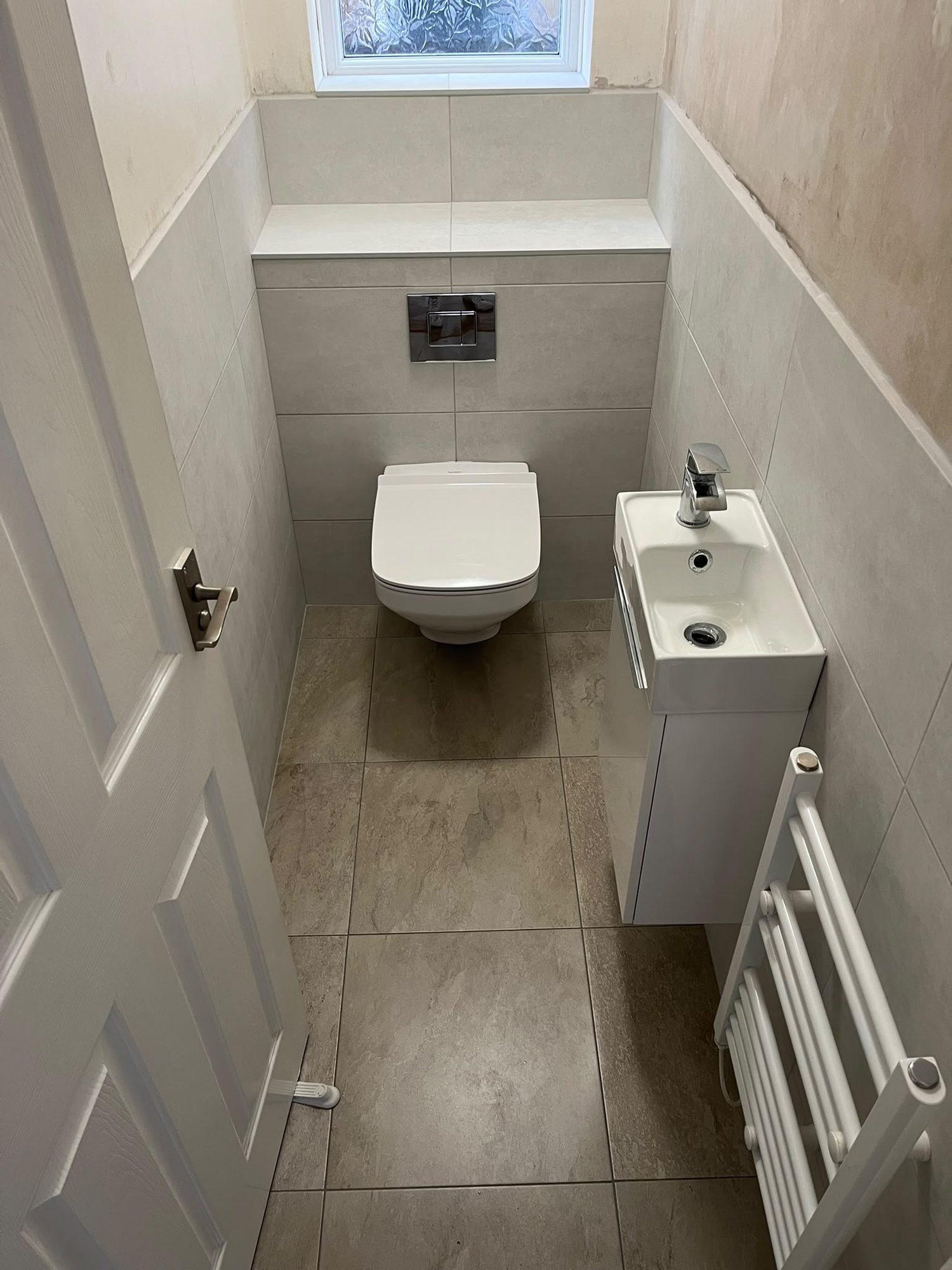 Small bathroom with wall-hung toilet, slim basin unit and stone-effect floor tiles