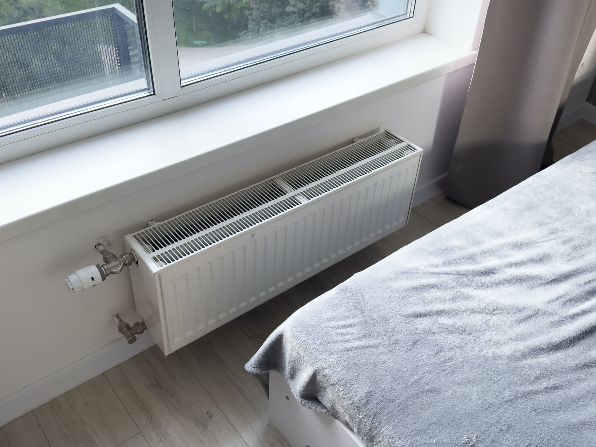 White panel radiator with thermostatic valve fitted under a bedroom window