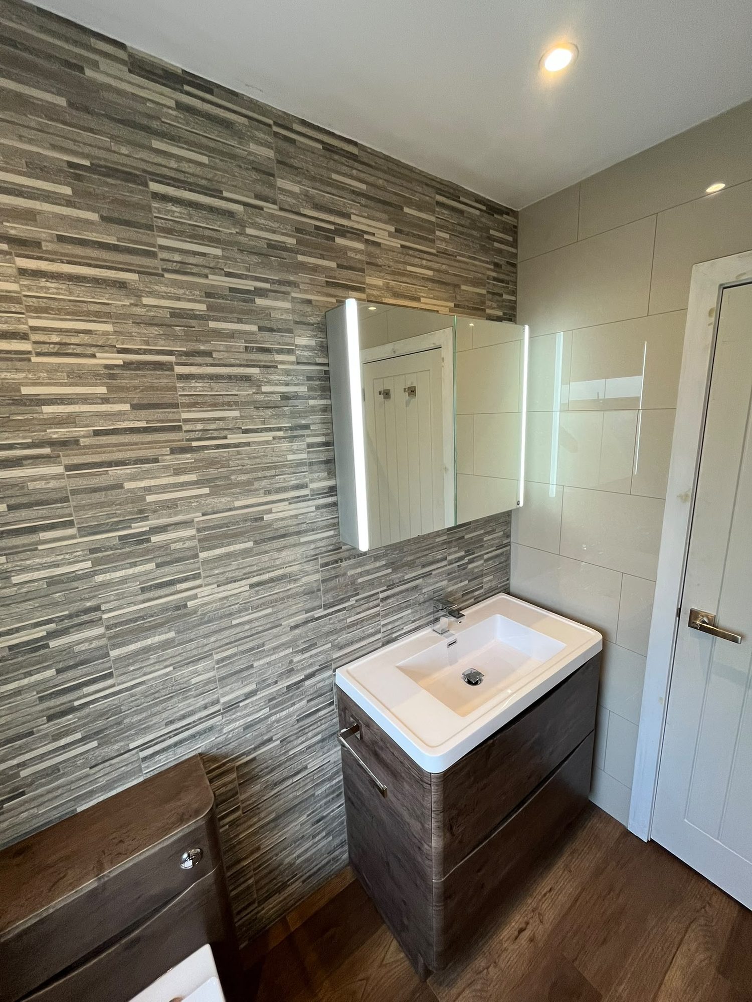Bathroom with split-face stone feature wall, vanity unit and mirrored cabinet