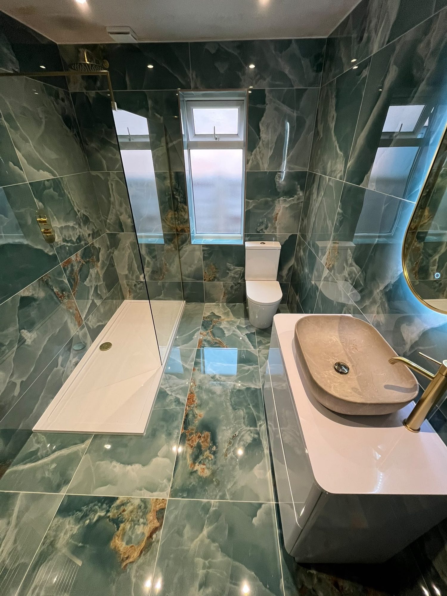 Green marble-effect shower room with walk-in shower, brass fittings and concealed plumbing by N Monk Plumbing & Heating